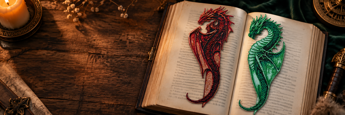 Two  dragon bookmarks, one red and one green, on the pages of an open book on a rustic wooden table with a candle and fantasy-themed props.