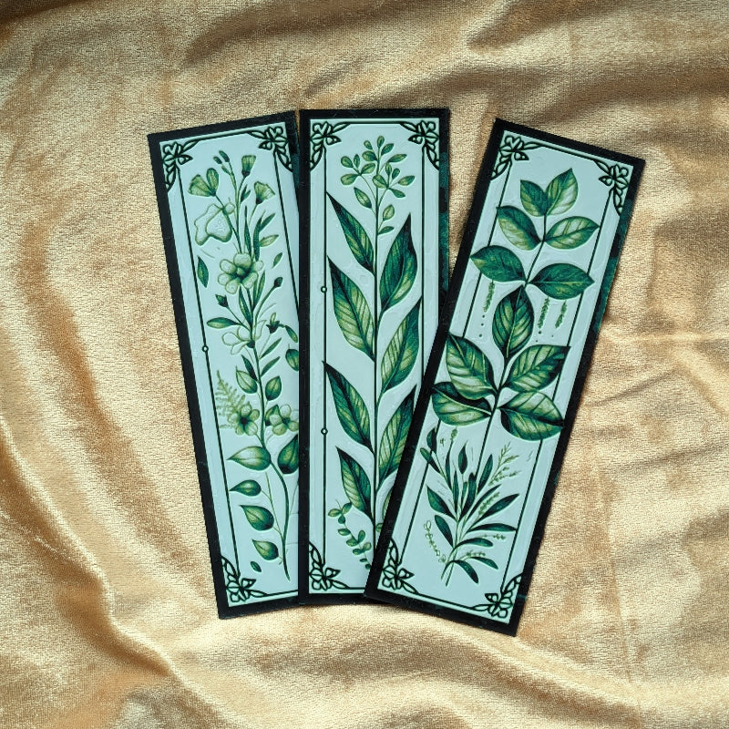 Close-up of botanical bookmark collection displaying detailed leaf illustrations and illuminated manuscript-inspired borders.