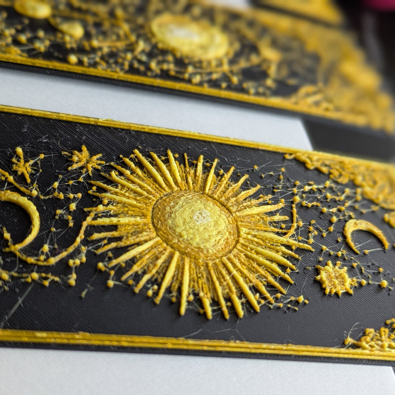 Close-up of gilded celestial bookmarks showing intricate gold texture and raised decorative details