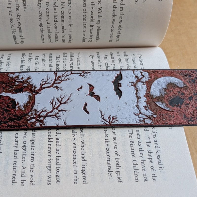 Close up of textured crescent moon and flying bats on gothic bookmark