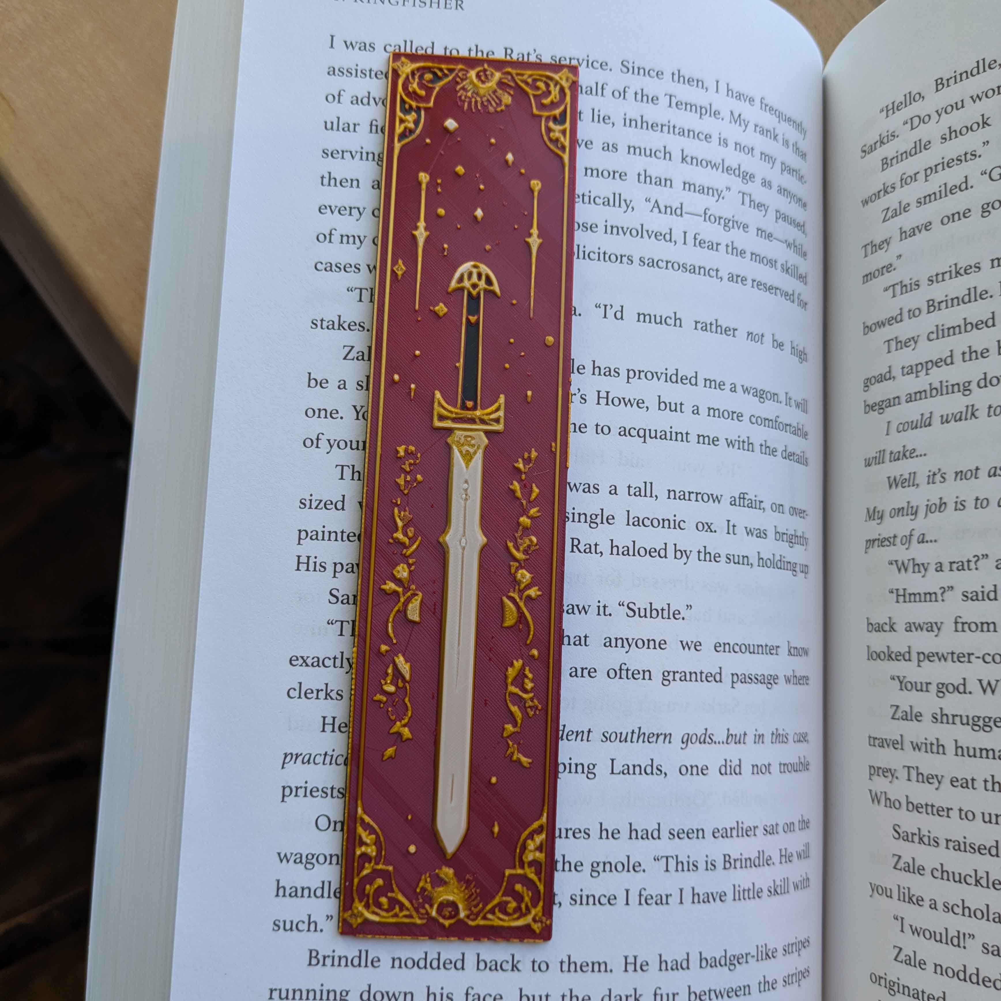 Crimson Arcana Sword Bookmark with a red and gold medieval sword design featuring gothic floral detailing.
