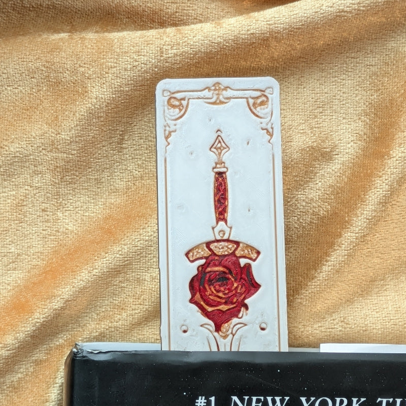 Close-up of sword and rose bookmark with textured surface and medieval styling
