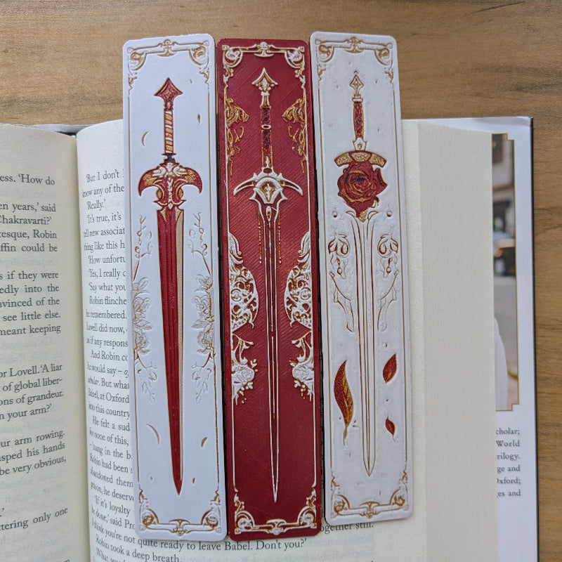 Set of three medieval sword bookmarks with red, ivory, and gold designs