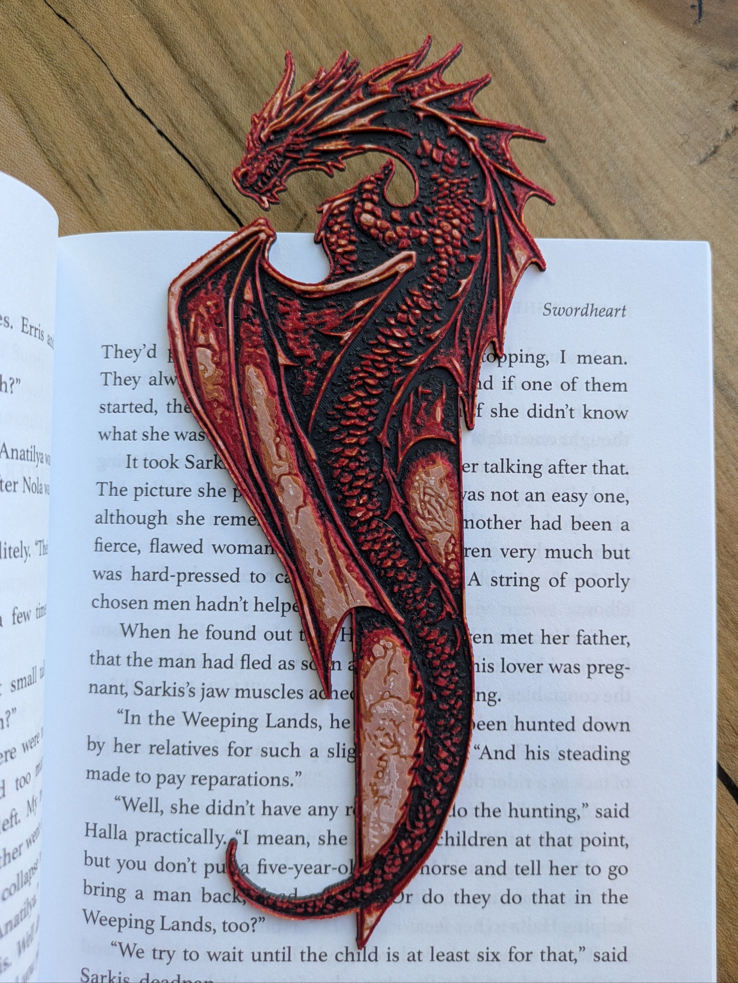 Handcrafted red dragon bookmark resting on an open book with intricate scales and vibrant red accents, designed for fantasy and gothic book lovers.