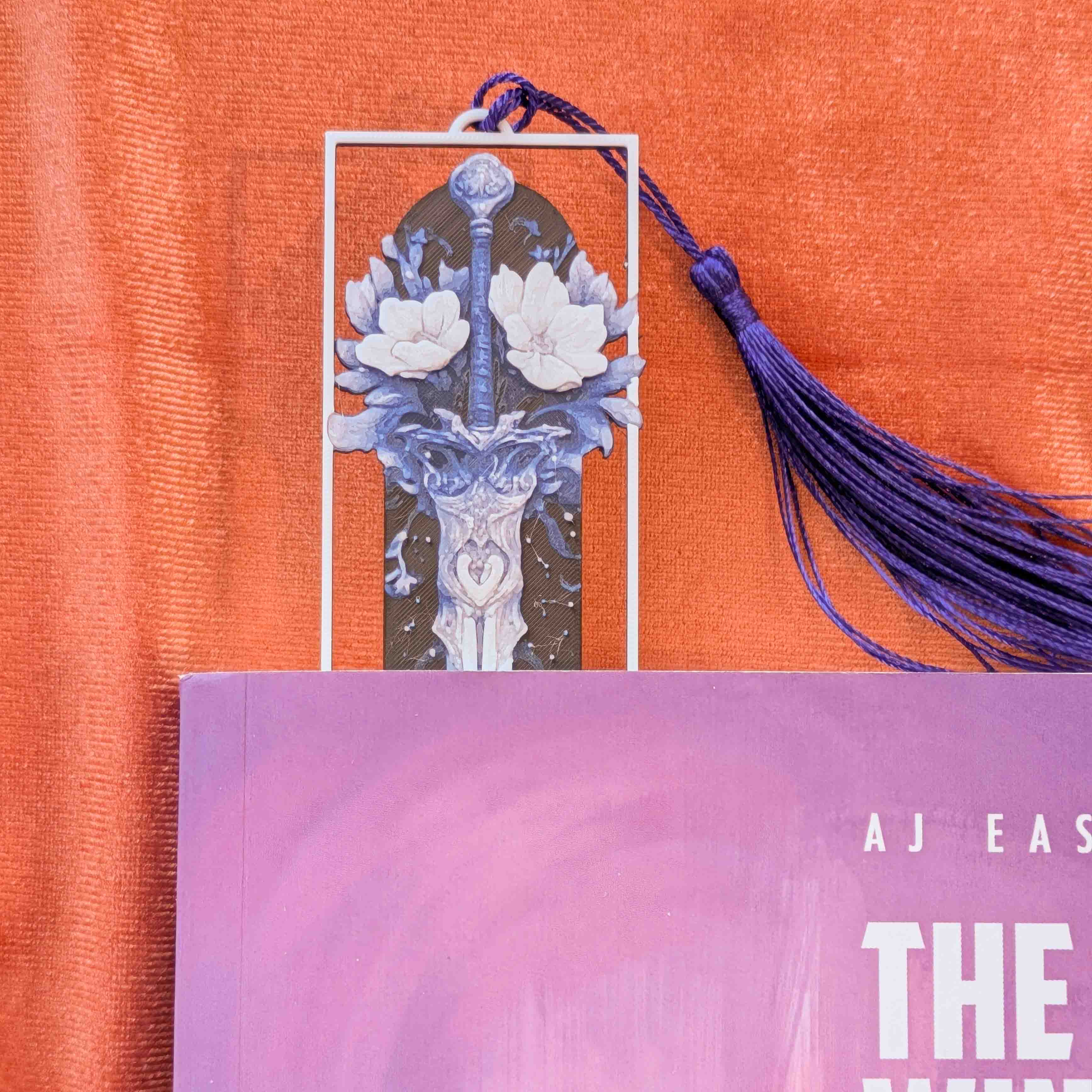 Close-up of floral elements surrounding the sword illustration on a fantasy bookmark