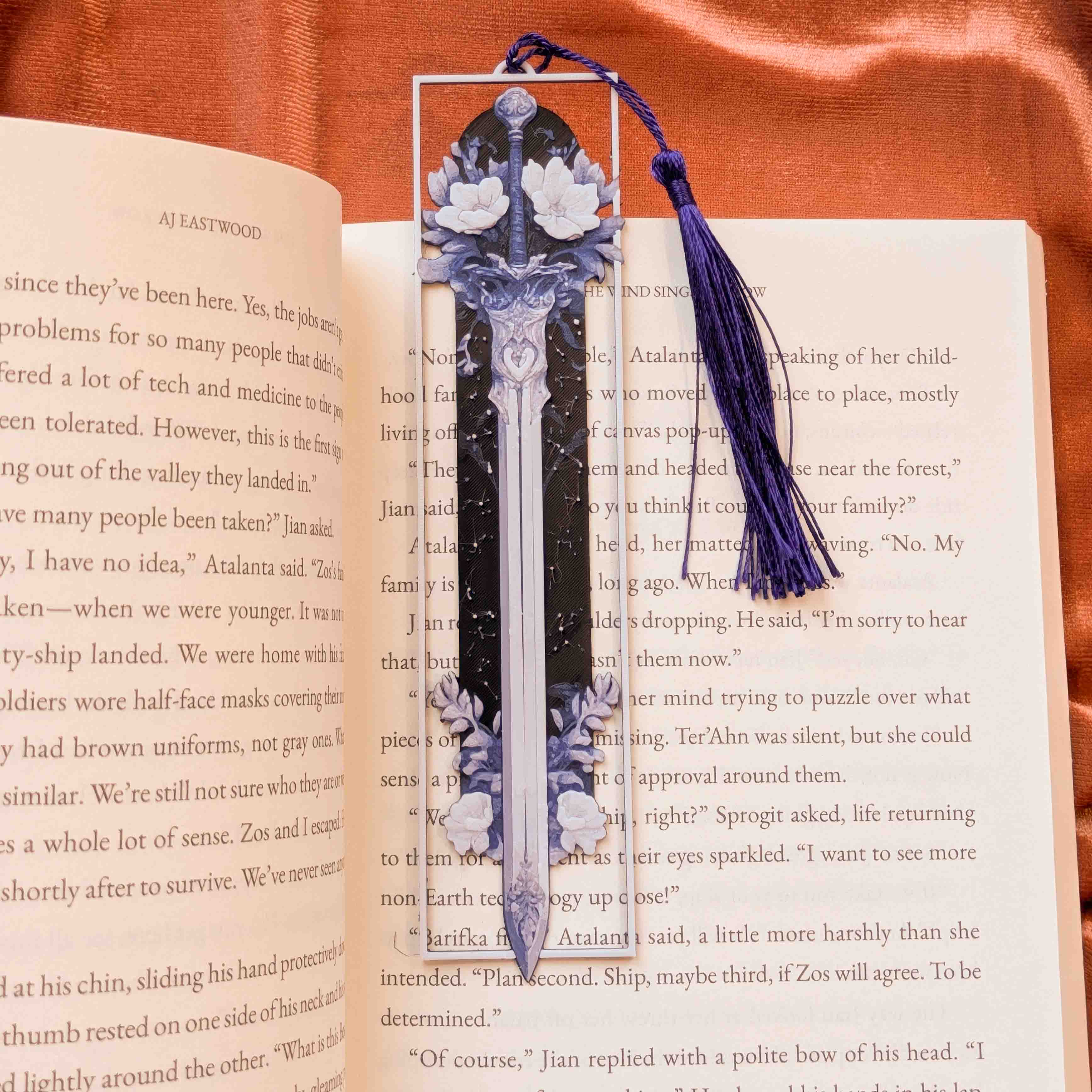 Long floral sword fantasy bookmark with a color-coordinated tassel placed in an open book