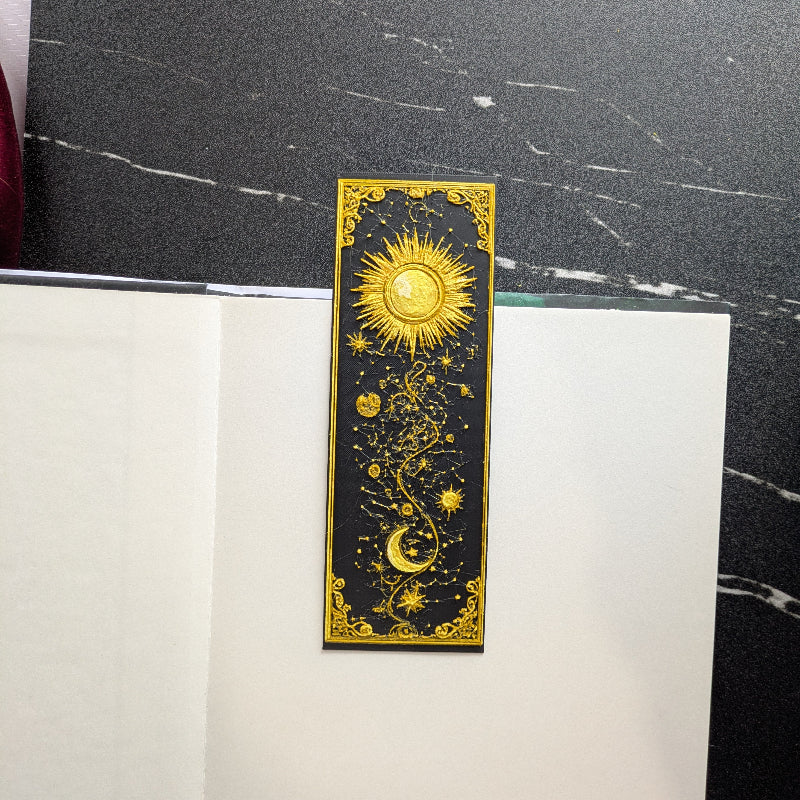 Gilded Sun and Moon celestial bookmark with gold sun, crescent moon, stars, and ornate black frame
