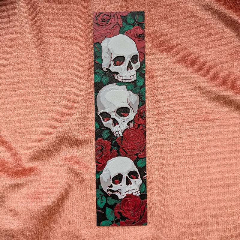 Set of gothic skull and rose bookmarks displayed together on soft fabric
