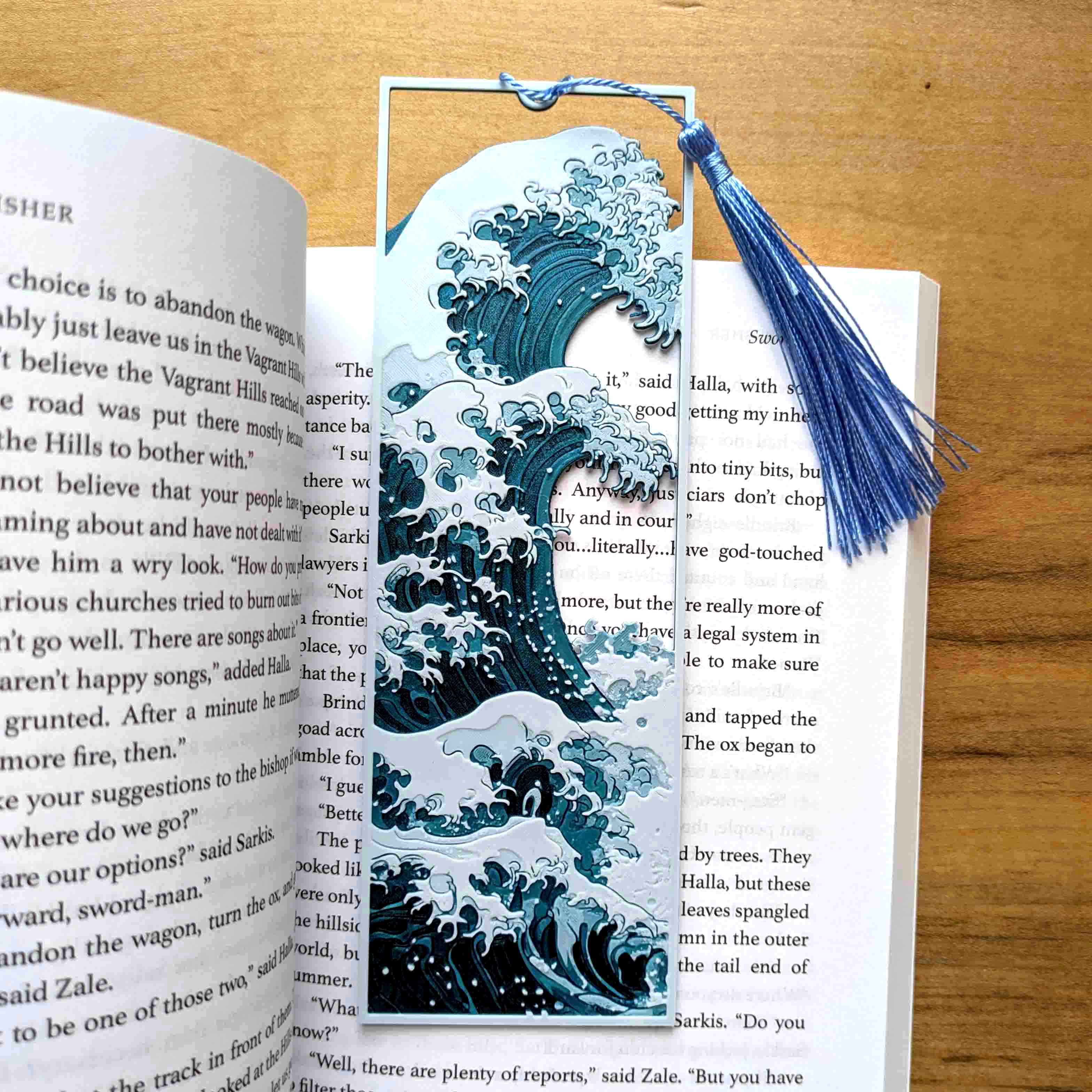 Textured great wave inspired art bookmark with layered blue wave design and tassel on open book