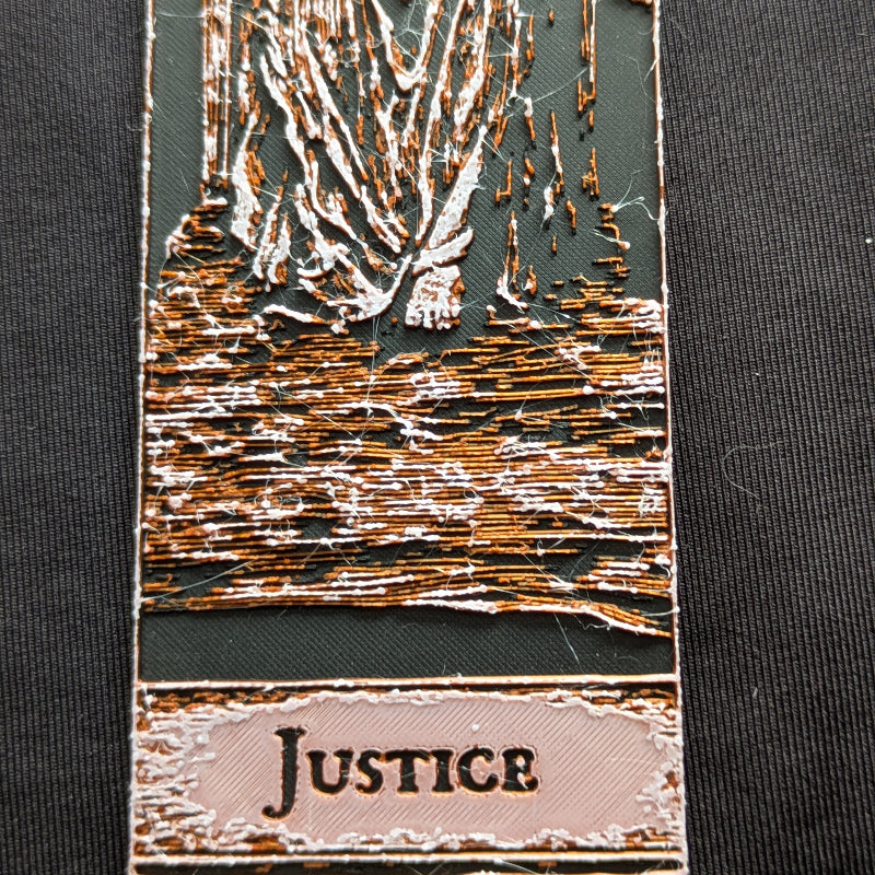 Close-up of the Justice tarot bookmark Classic Edition, showing the draped robe, ground texture, and Justice nameplate