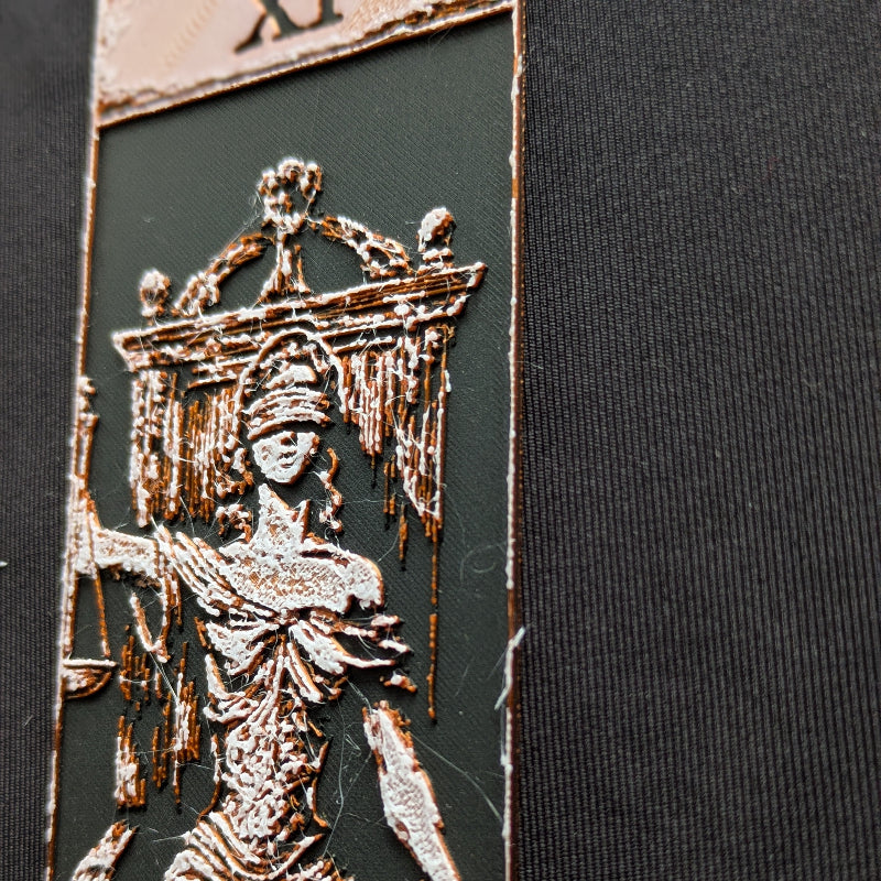 Close-up of the Justice tarot bookmark Classic Edition, showing textured copper-toned relief detailing on the blindfolded figure and canopy