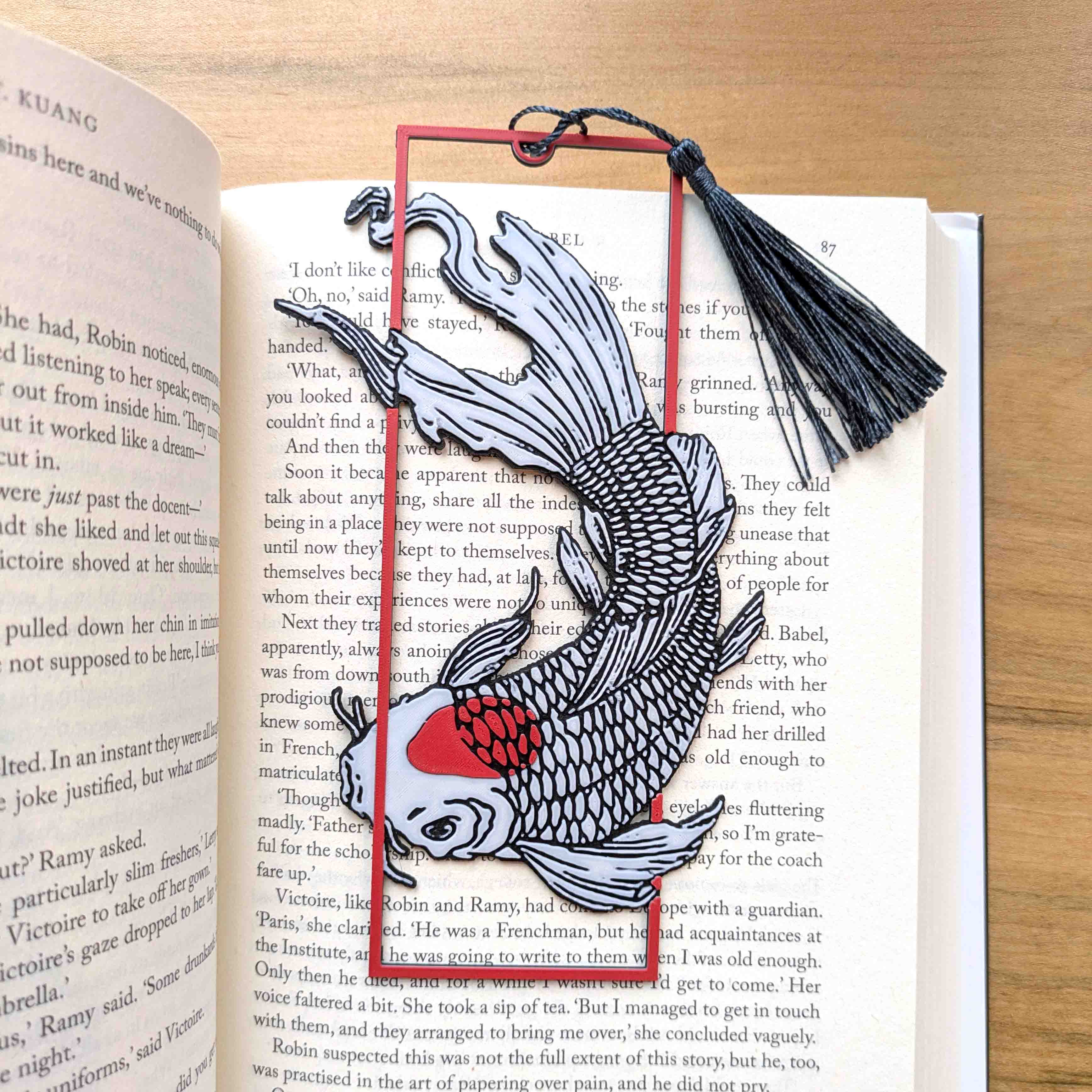 Japanese koi fish bookmark with red accent and black tassel resting in open book