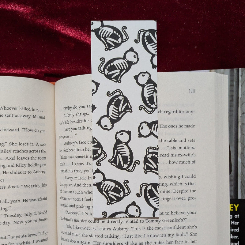 Black and white medieval cat skeleton pattern bookmark inside an open book