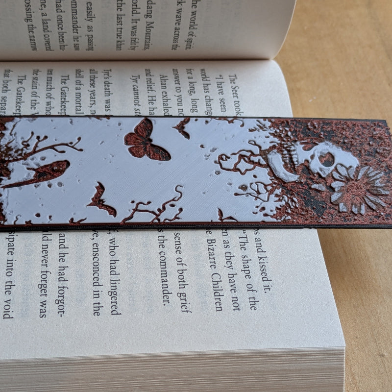 Close up of hand painted skull, butterfly, and bat detail on bookmark