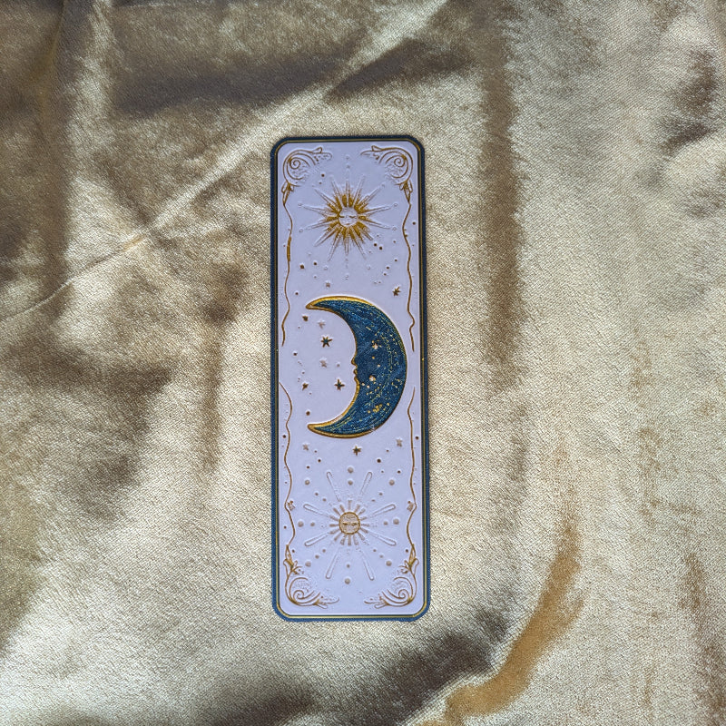 Gold embossed crescent moon celestial bookmark on ivory background with sun motifs