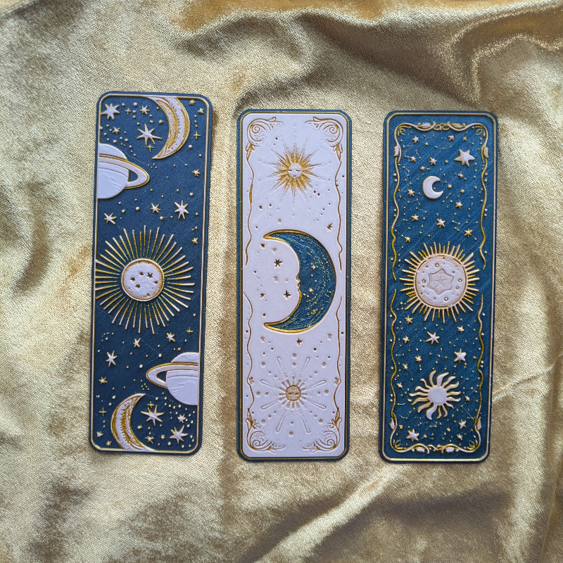 Set of three celestial bookmarks, Saturn and stars, moonlit ivory, and midnight sun and moon designs