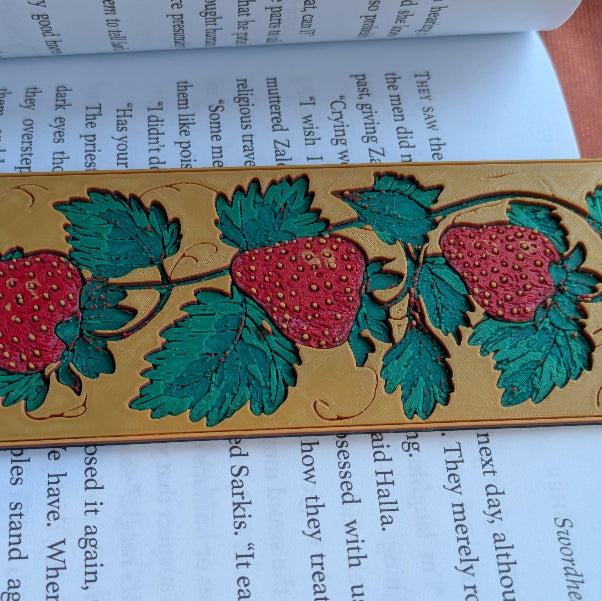 Medieval inspired strawberry vine bookmark placed inside an open book in a cozy reading nook with warm natural light