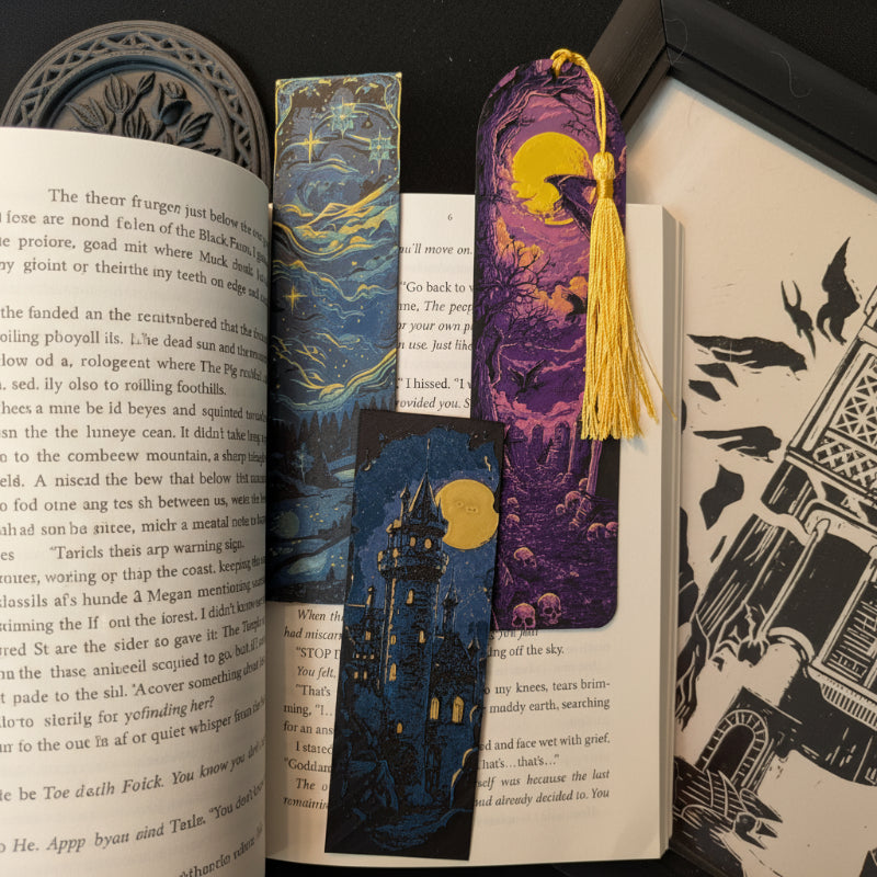 Three-bookmark One More Chapter Bundle featuring Starry Night Sky, Moonlit Castle I, and Moonlit Graveyard displayed across an open book.