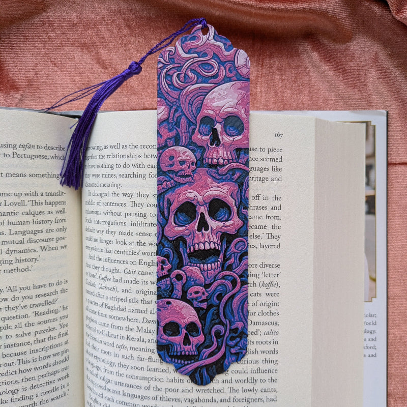 Pink gothic skull bookmark with violet tassel resting inside an open book