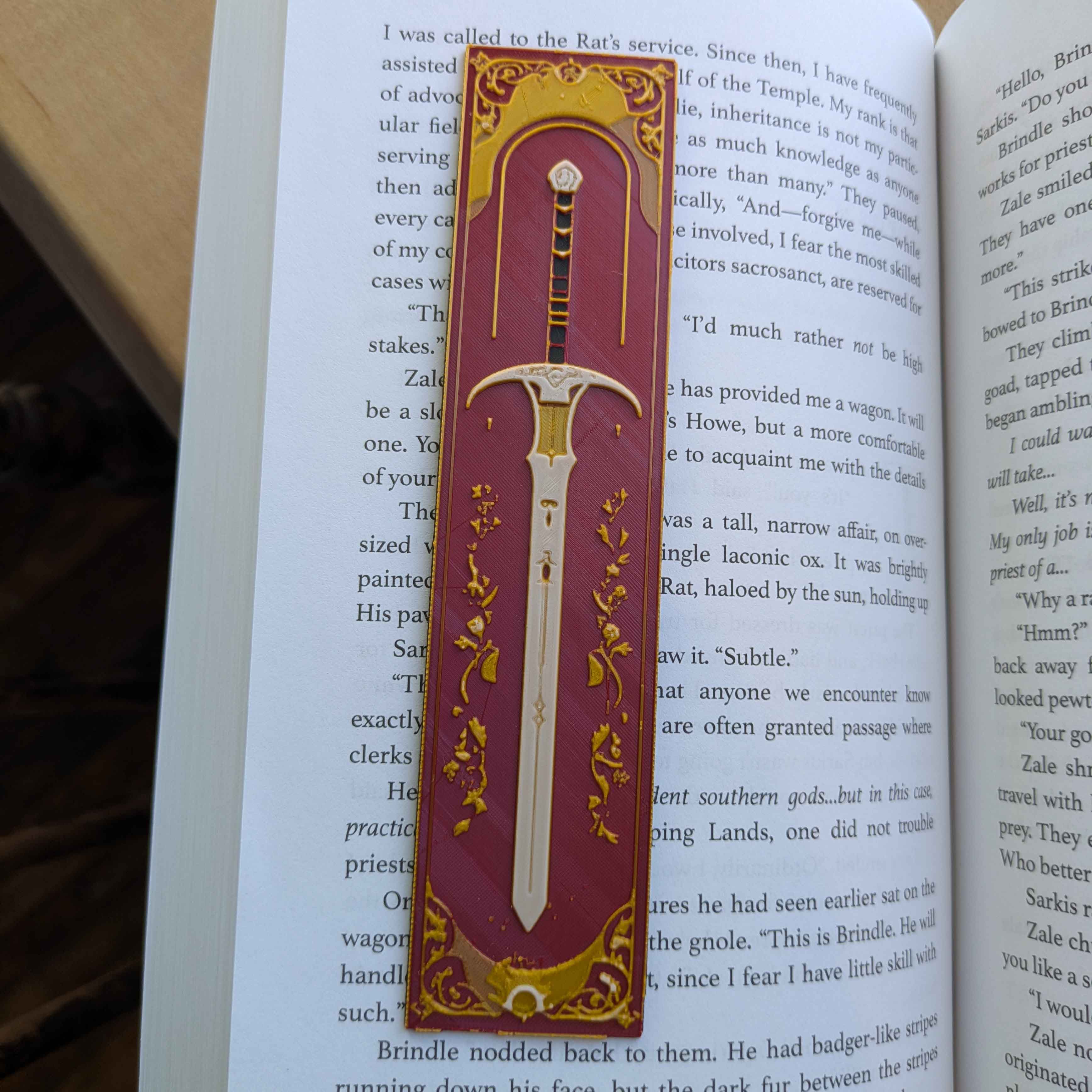 Rose Eclipse Sword Bookmark with a gold sword on a rose-red background adorned with celestial stars and gothic floral accents.