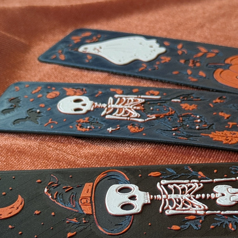 Close up of raised skeleton, bat, and pumpkin details on autumn bookmark