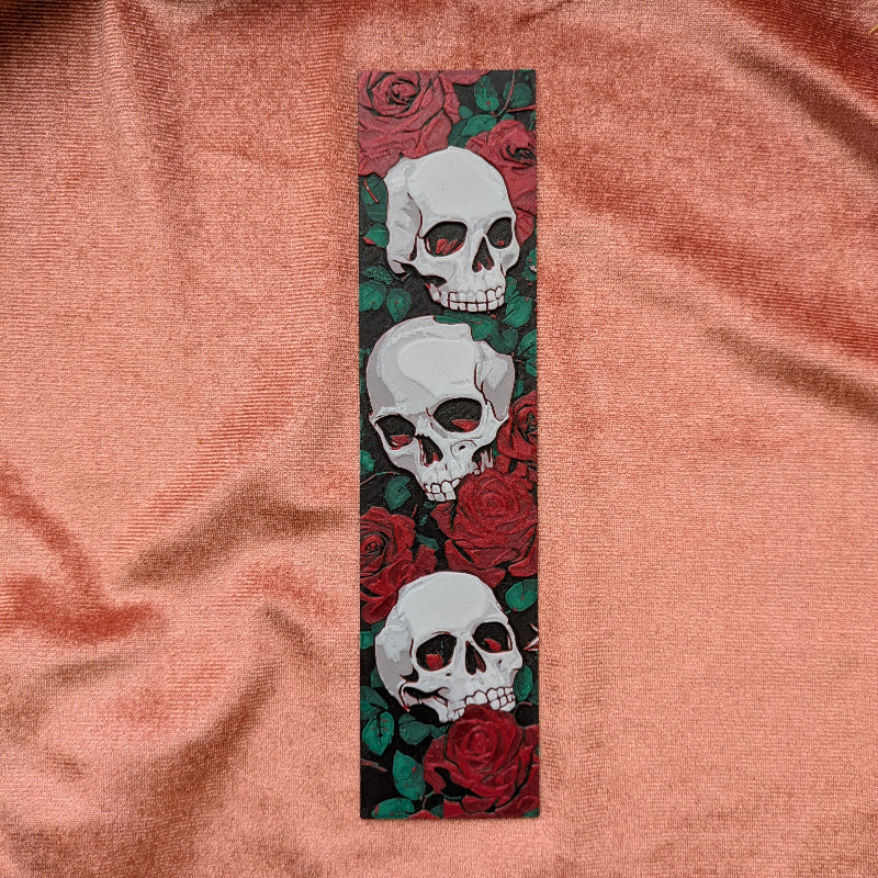 Decorative bookmark with skulls and roses on a pink fabric background