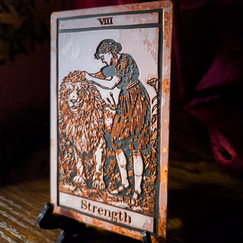 Collector Edition Strength tarot bookmark displayed in an open book, featuring the woman and lion Major Arcana artwork.