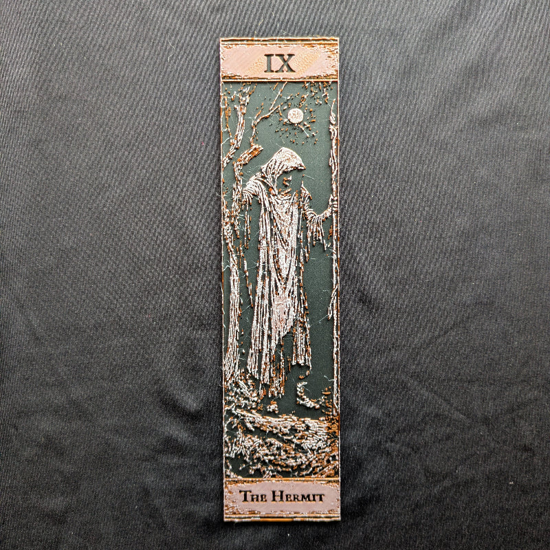 The Hermit tarot bookmark, Classic Edition, a slim textured design showing a cloaked figure, bare trees, and moon on a dark ground
