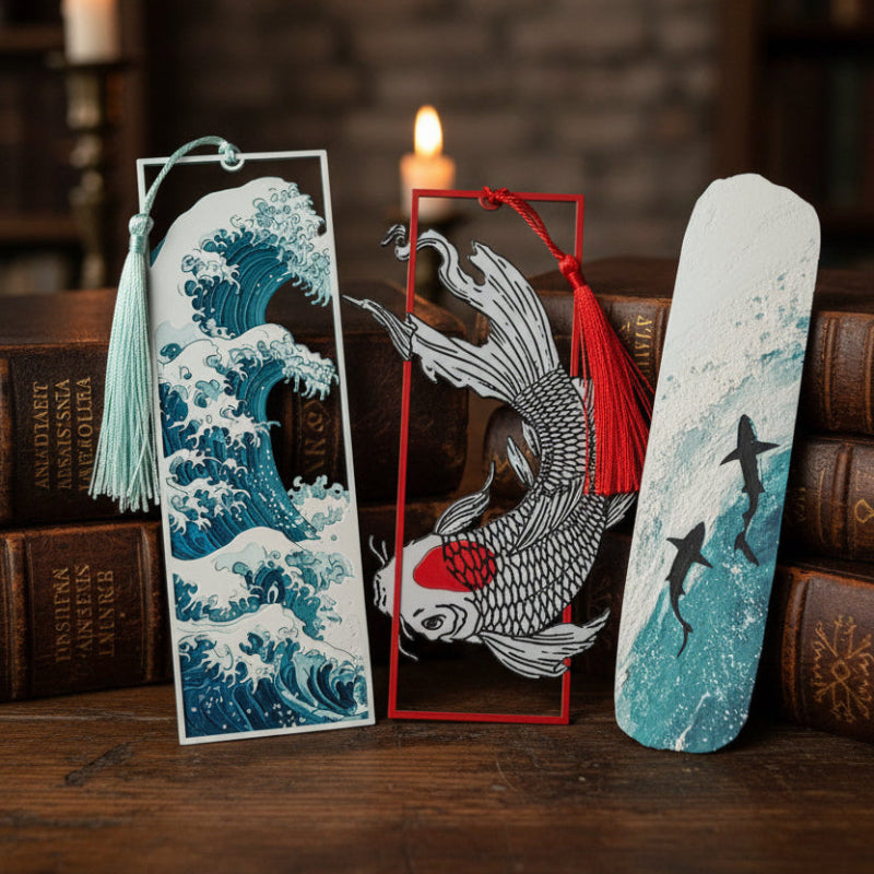 Three decorative bookmarks with koi fish and wave designs on a dark surface.